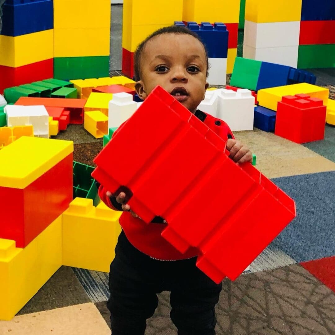 A toddler holding onto a red object in front of him.