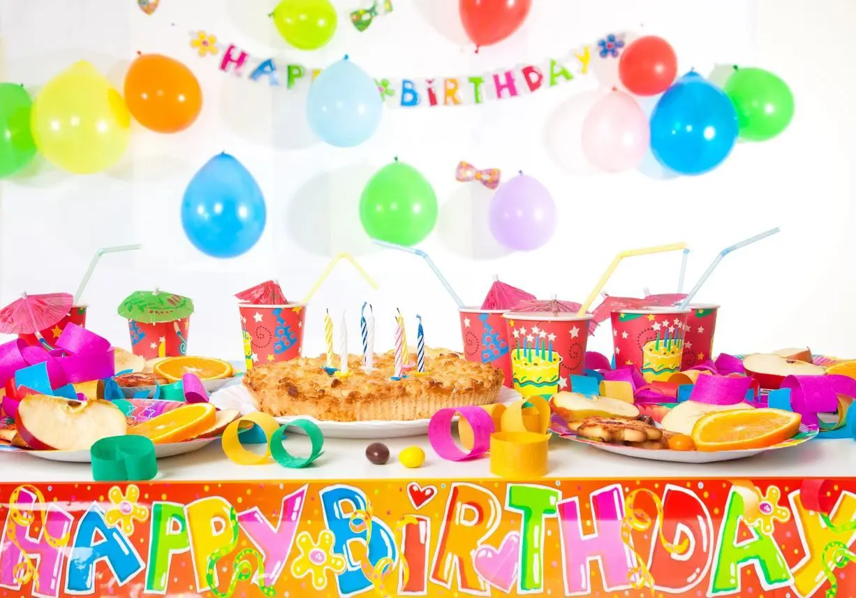 A birthday party with balloons and cake on the table.